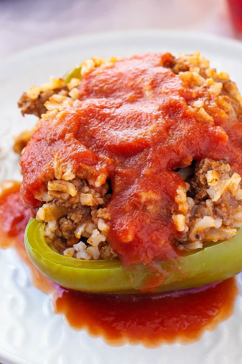 Old fashioned stuffed bell pepper topped with tomato sauce on a white plate