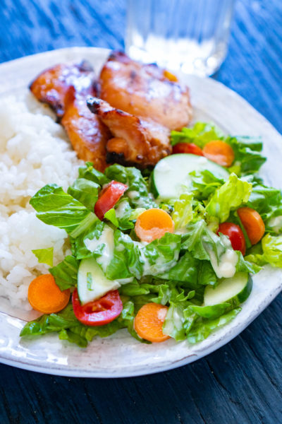 Teriyaki plate with chicken, rice, and salad topped with teriyaki salad dressing