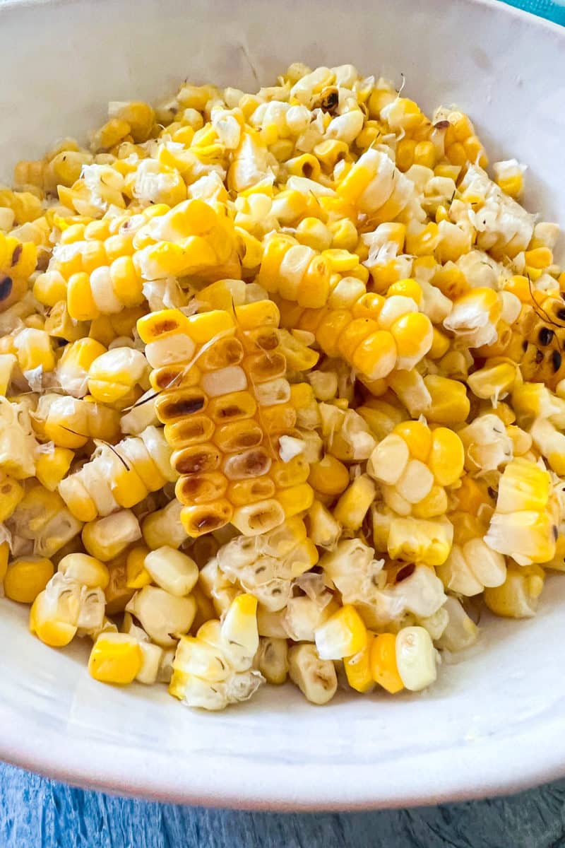 A white bowl of corn kernels with char marks from grilling