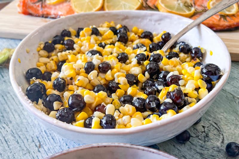 Blueberry corn salad in a large white serving bowl with spoon
