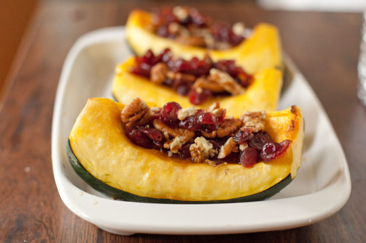 Vegetarian recipe for stuffed acorn squash that tastes like fall. Roasted acorn squash stuffed with crunchy pecans, tangy cranberries, & sweet brown sugar. From EatingRichly.com