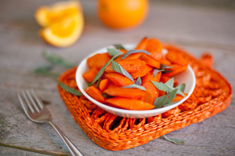 Sliced orange maple roasted carrots with fresh sage leaves