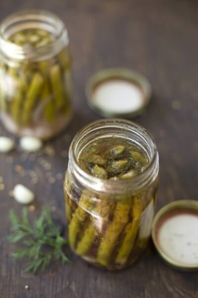 Pickled Asparagus in jars on a brown wood surface