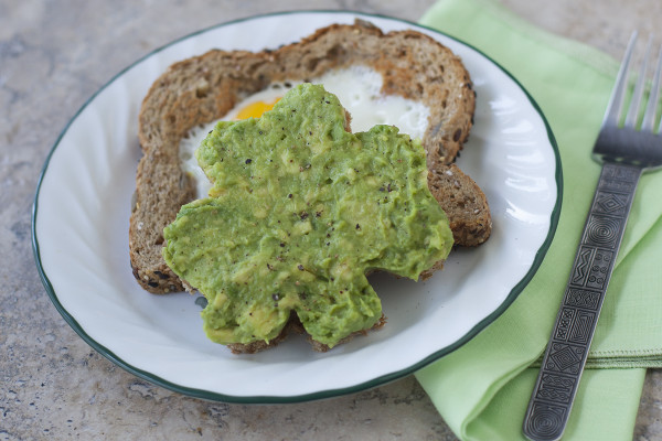 A healthy St. Patrick's Day breakfast with whole grain avocado shamrock toast and egg in a basket - EatingRichly.com