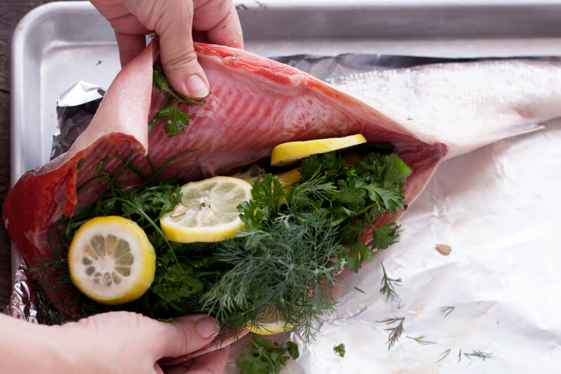 Learn how to cook whole salmon in the oven, the easy way! This healthy recipe for whole salmon stuffed with lemon & herbs makes salmon an affordable option. From EatingRichly.com