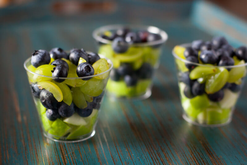 This fruit salad is a healthy football appetizer that's perfect for Seahawks fans. Green apples and grapes are layered with blueberries in individual servings for a football snack that is so easy to make, a toddler can do it! Part of #MiniChefMondays on EatingRichly.com