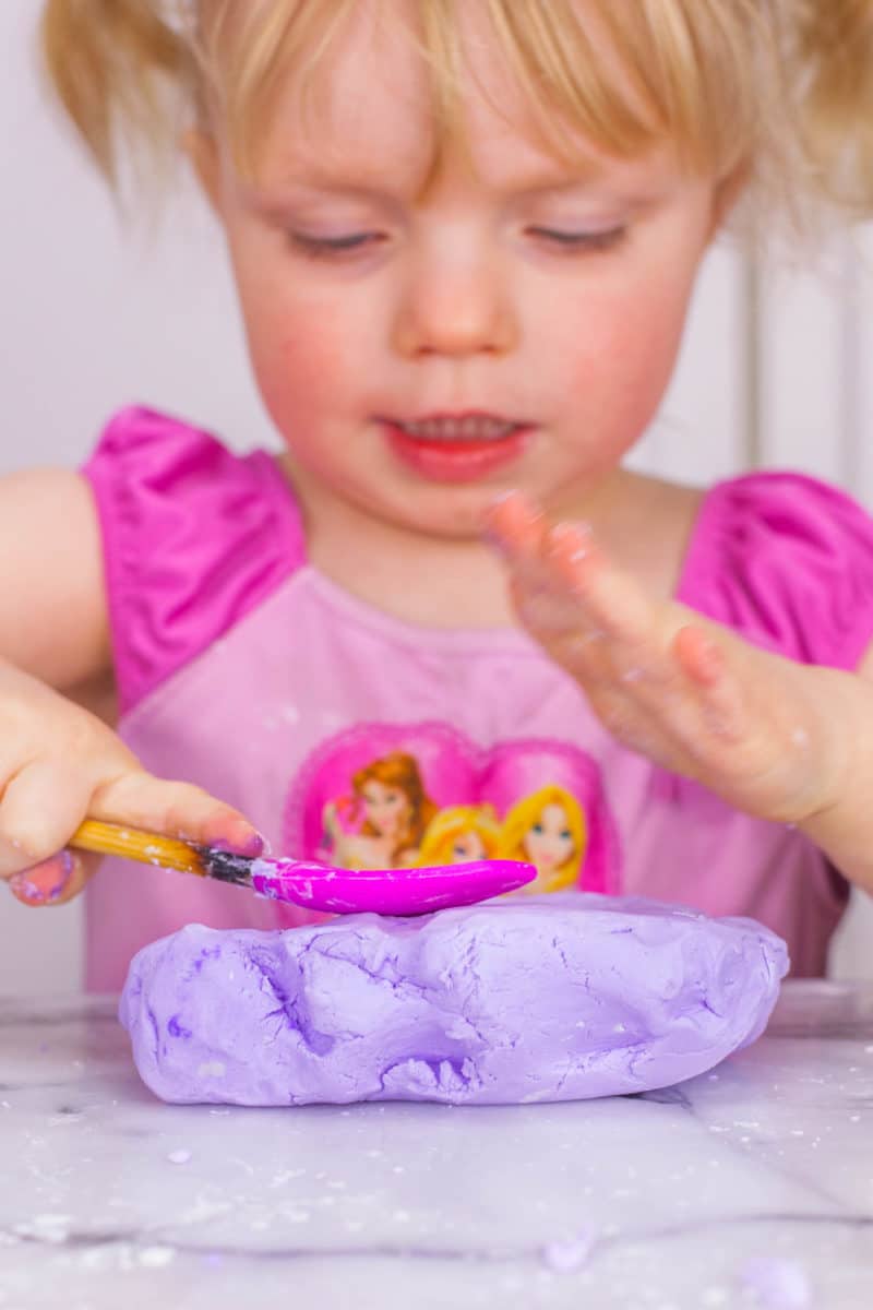 Girl pressing on homemade silly putty with a spatula