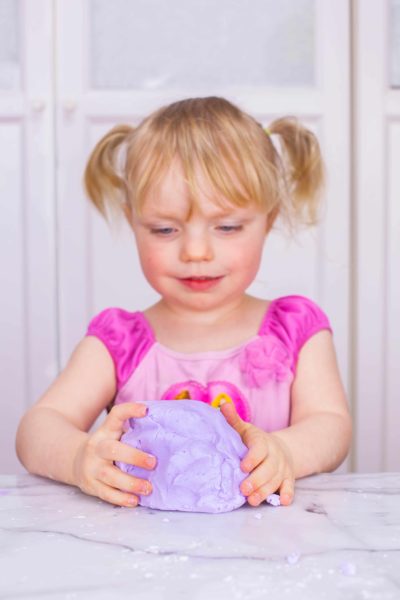 Little Girl playing with purple homemade silly putty