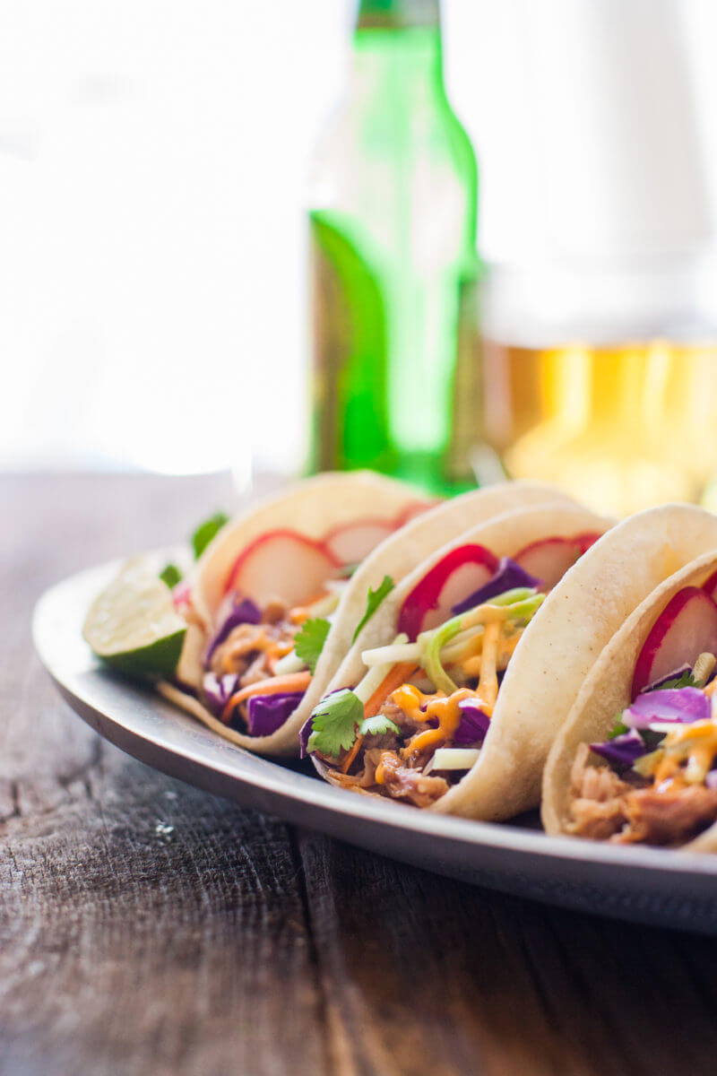 Korean tacos filled with easy flavorful crockpot pulled pork, crunchy veggies, and sweet and spicy sauces. You could start your own food truck with these! From EatingRichly.com