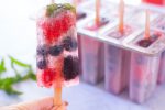 Refreshing summer sangria berry punch popsicles made with Riesling, sparkling wine, summer berries, fresh mint, triple sec, & lime. Perfect for backyard parties! From EatingRichly.com