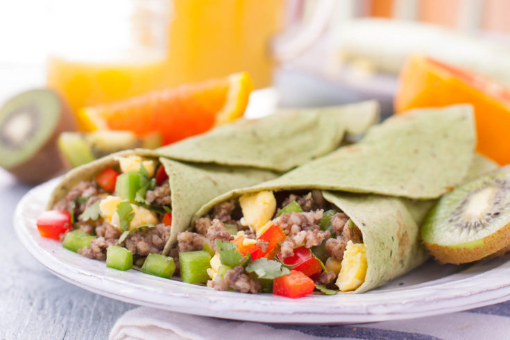 Breakfast Burritos on a plate with juice and fruit