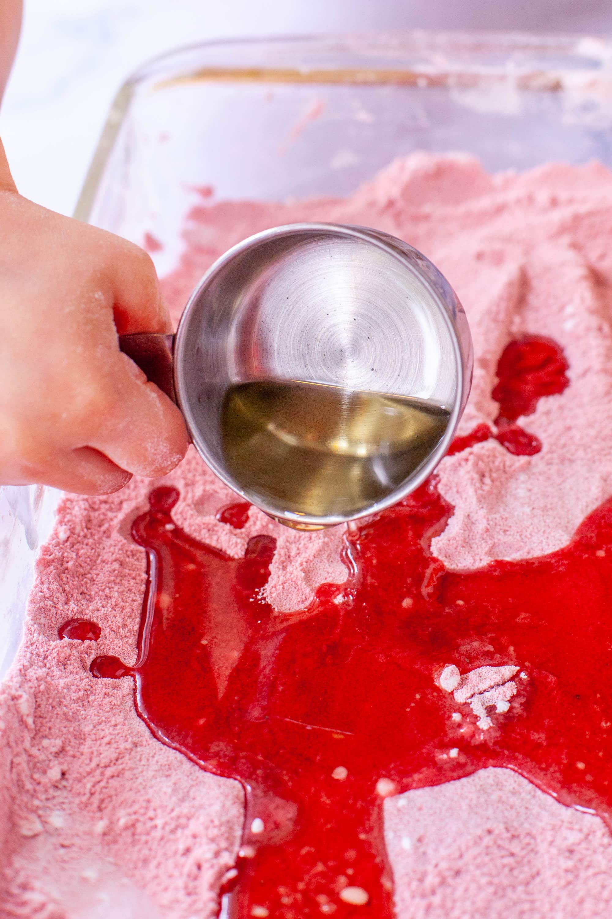 Pouring oil into sand and cornstarch for DIY kinetic sand