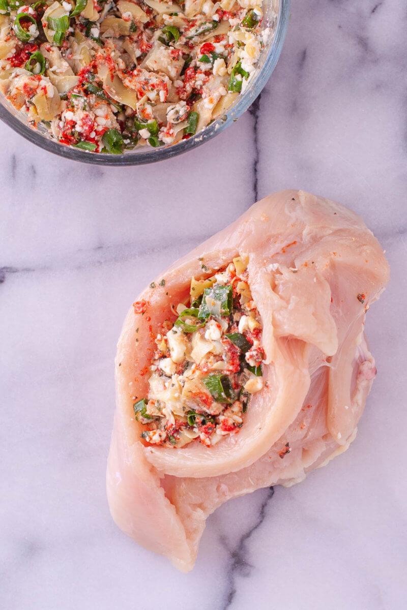 This keto stuffed chicken is easy to make and packed with Mediterranean flavors like artichokes, roasted red peppers, feta, green onions, and oregano. 