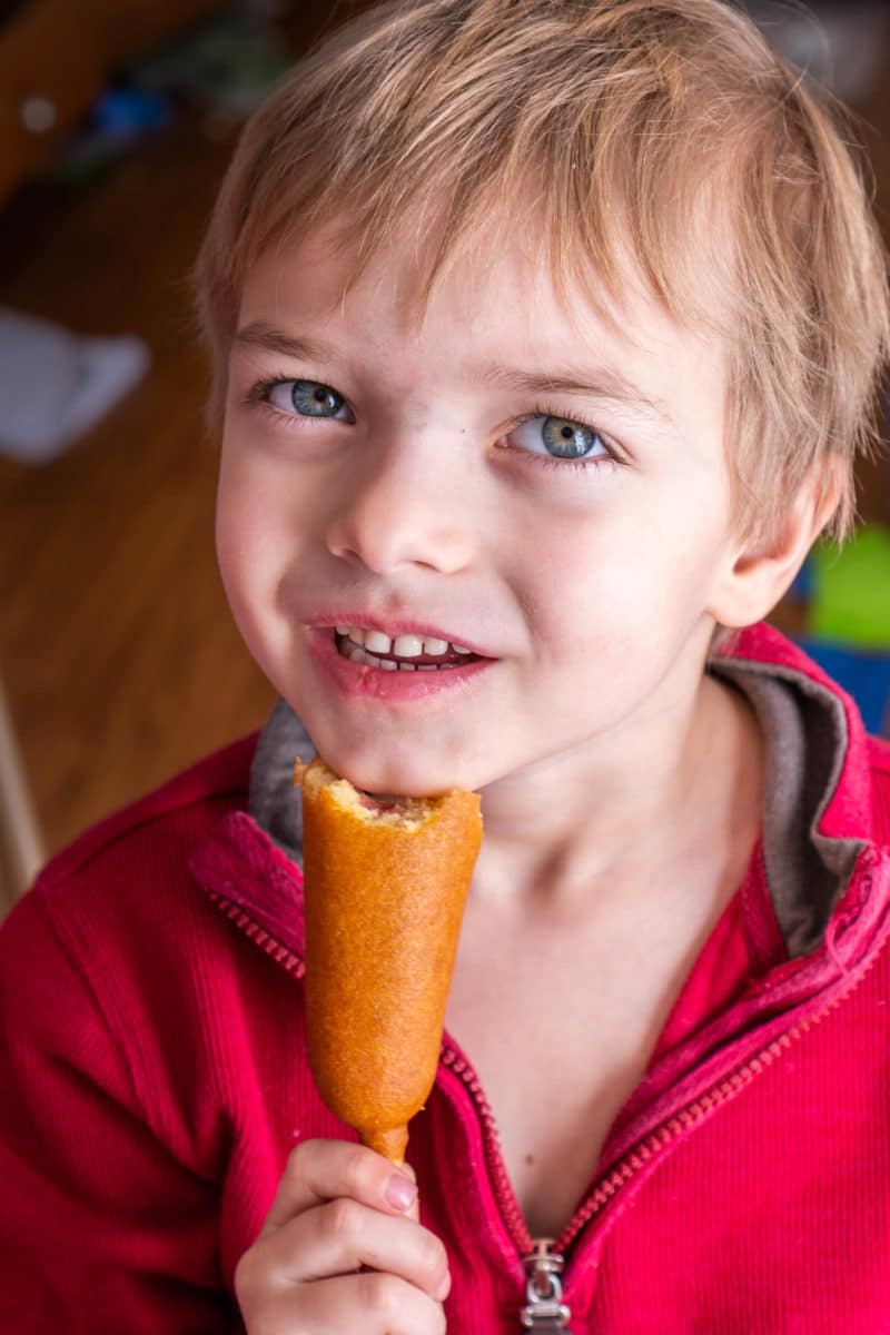 Child eating corn dog at football watch party