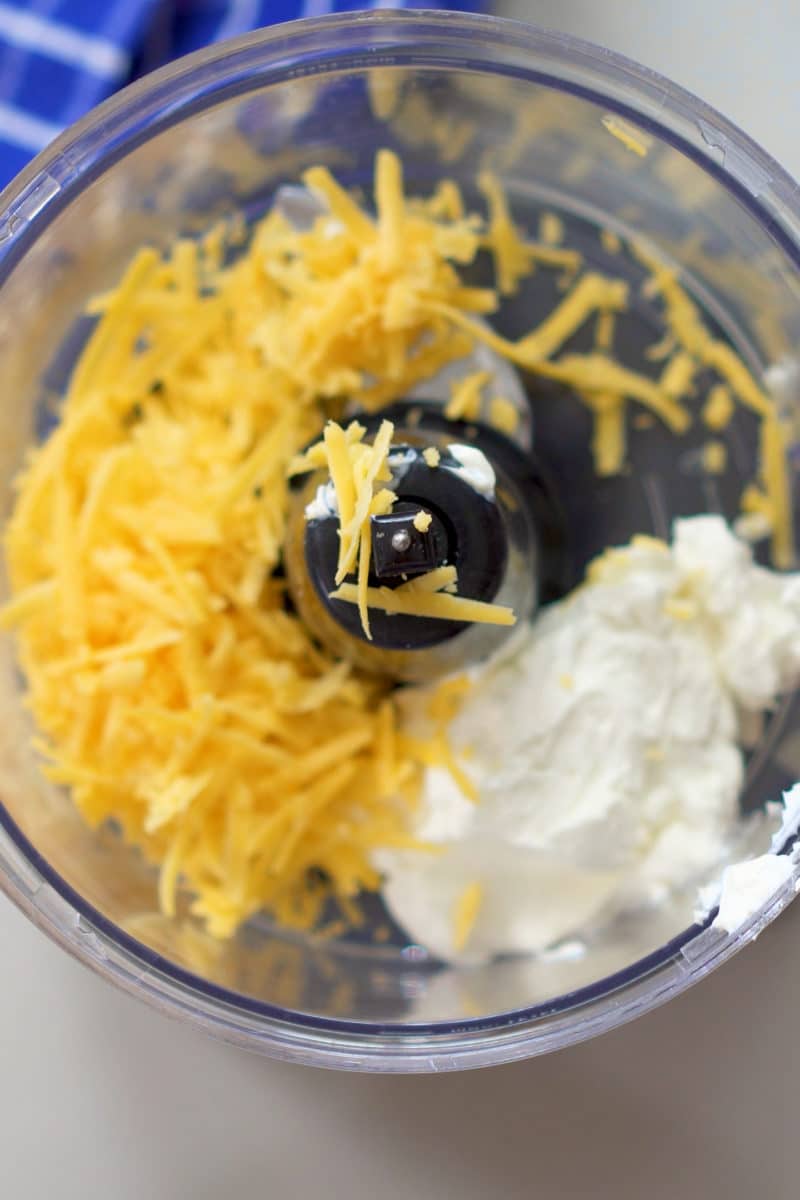 food processor with shredded cheddar and cream cheese in it
