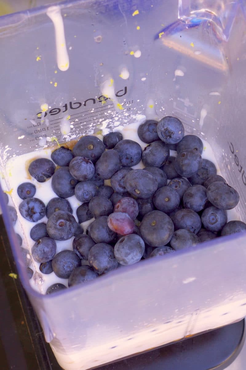 Blueberries and other ingredients in a blender to make ice cream