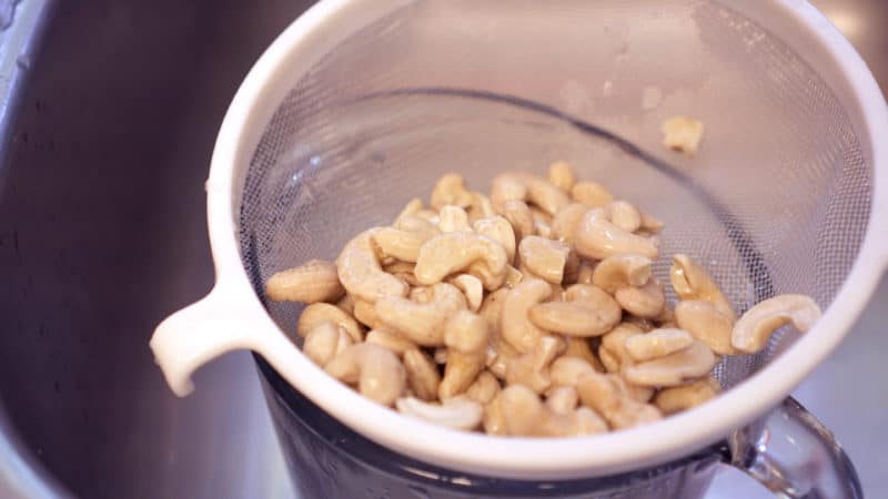 draining soaked cashews in a strainer