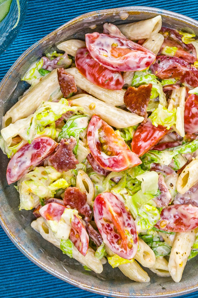 Bowl with penne pasta, sliced cherry tomatoes, lettuce, and turkey bacon in creamy dressing