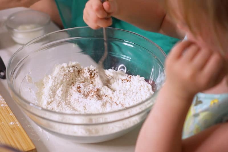 Child Mixing dry ingredients in glass bowl for muffins