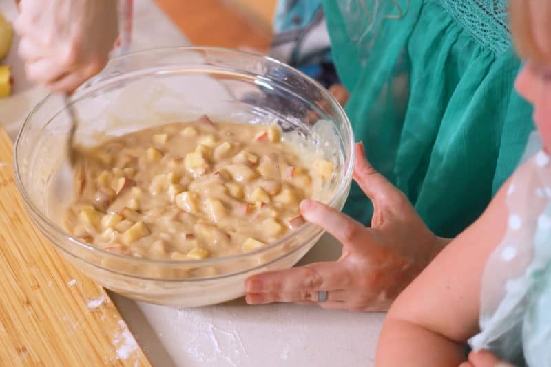 Woman's hands mixing apple muffin batter in a glass bowl