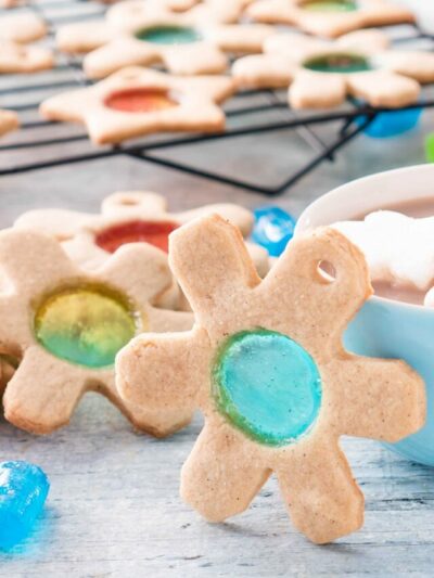 Snowflake shaped sugar cookie with blue circle of Jolly Rancher stained glass