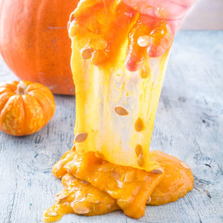 Hand stretching Pumpkin Slime with pumpkin seeds in it