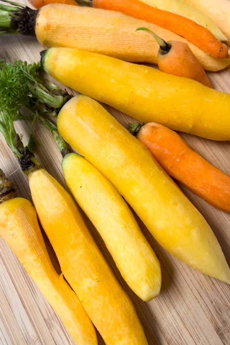 Peeled yellow and orange carrots with greens attached
